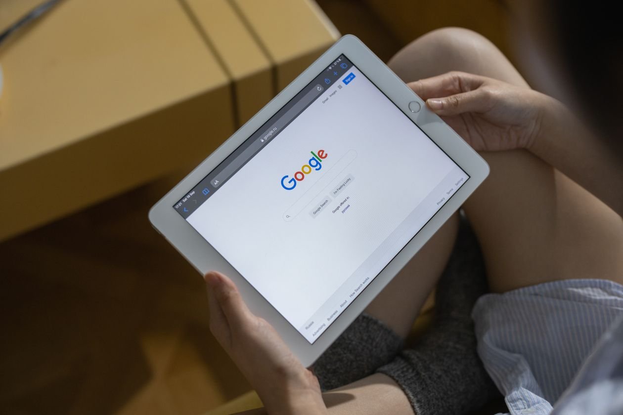Person sitting on a couch, tablet showing Google search