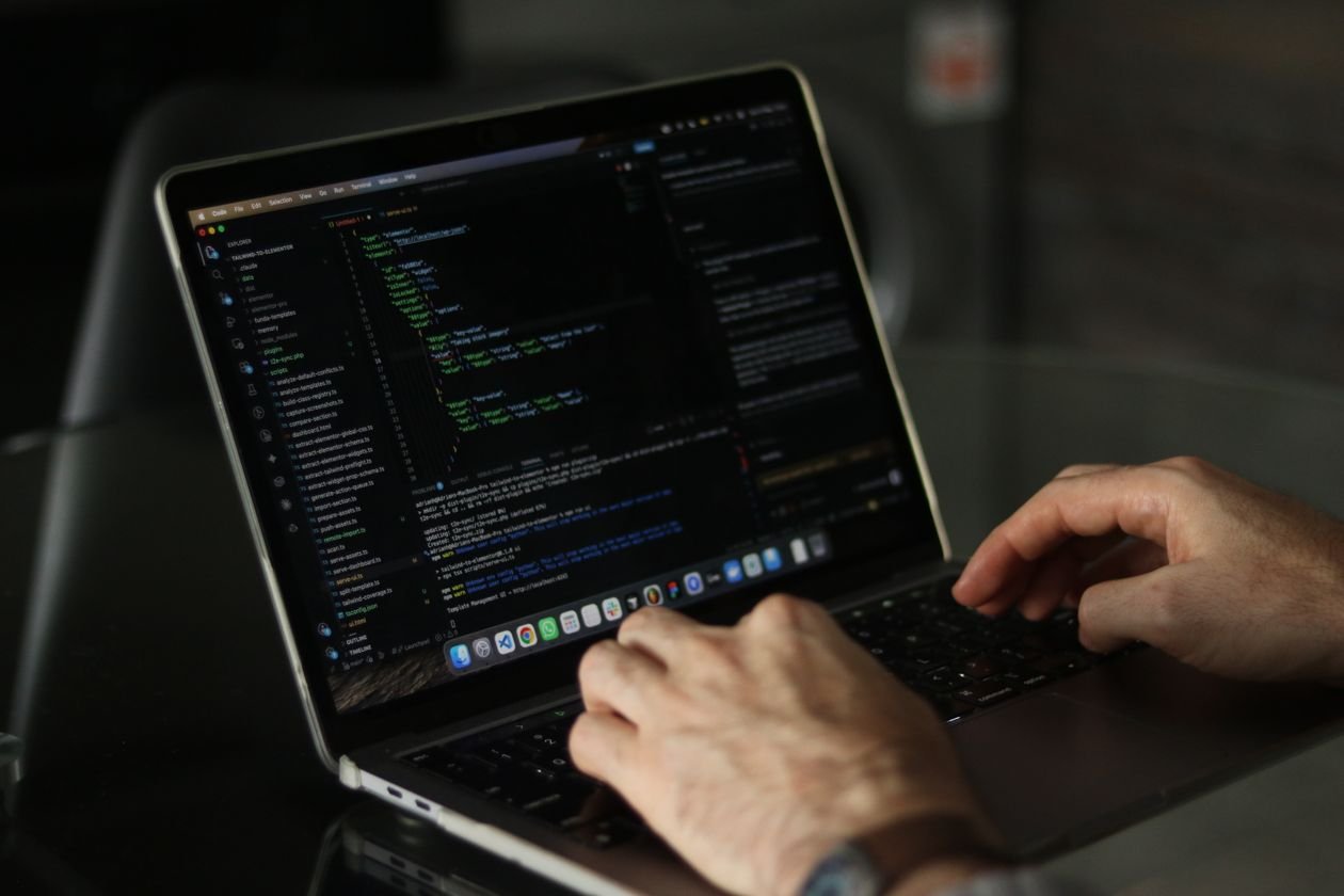 Close-up tangan coding di laptop, berfokus pada produktivitas pemrograman