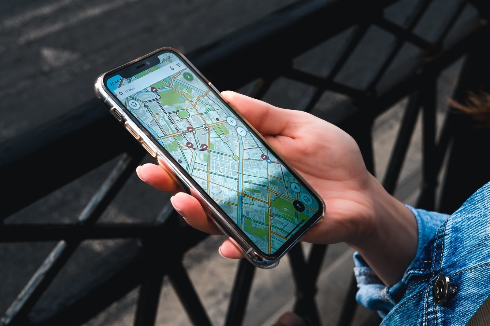 An outdoor close-up of a hand holding a smartphone displaying a map application