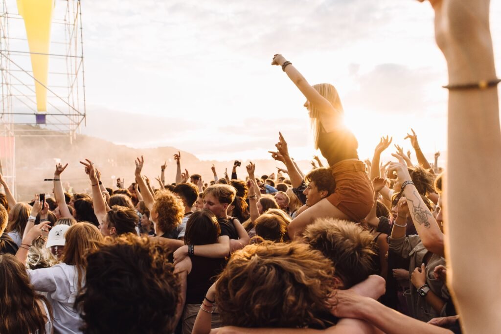 Kerumunan energik menikmati musik live di sebuah festival saat matahari terbenam