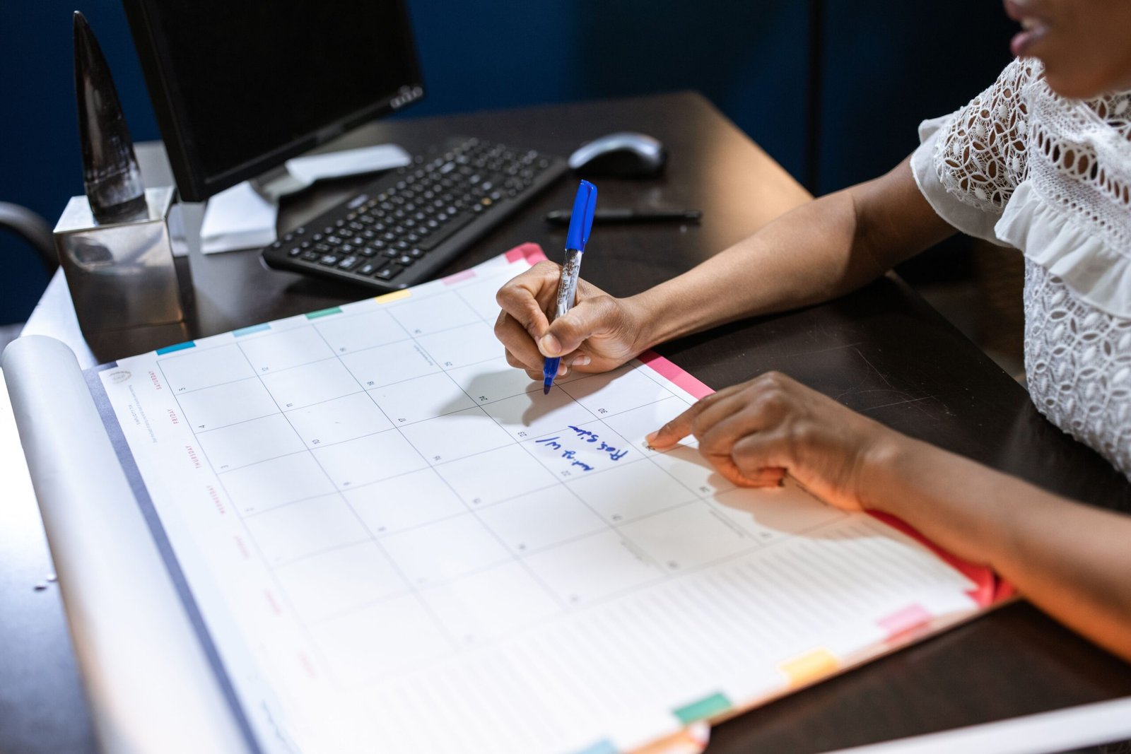 Orang yang menulis catatan penting di kalender meja dengan pena, diatur di kantor