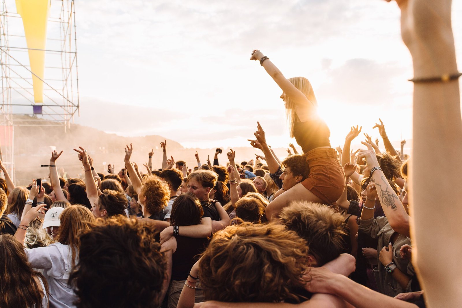 Kerumunan energik menikmati musik live di sebuah festival saat matahari terbenam