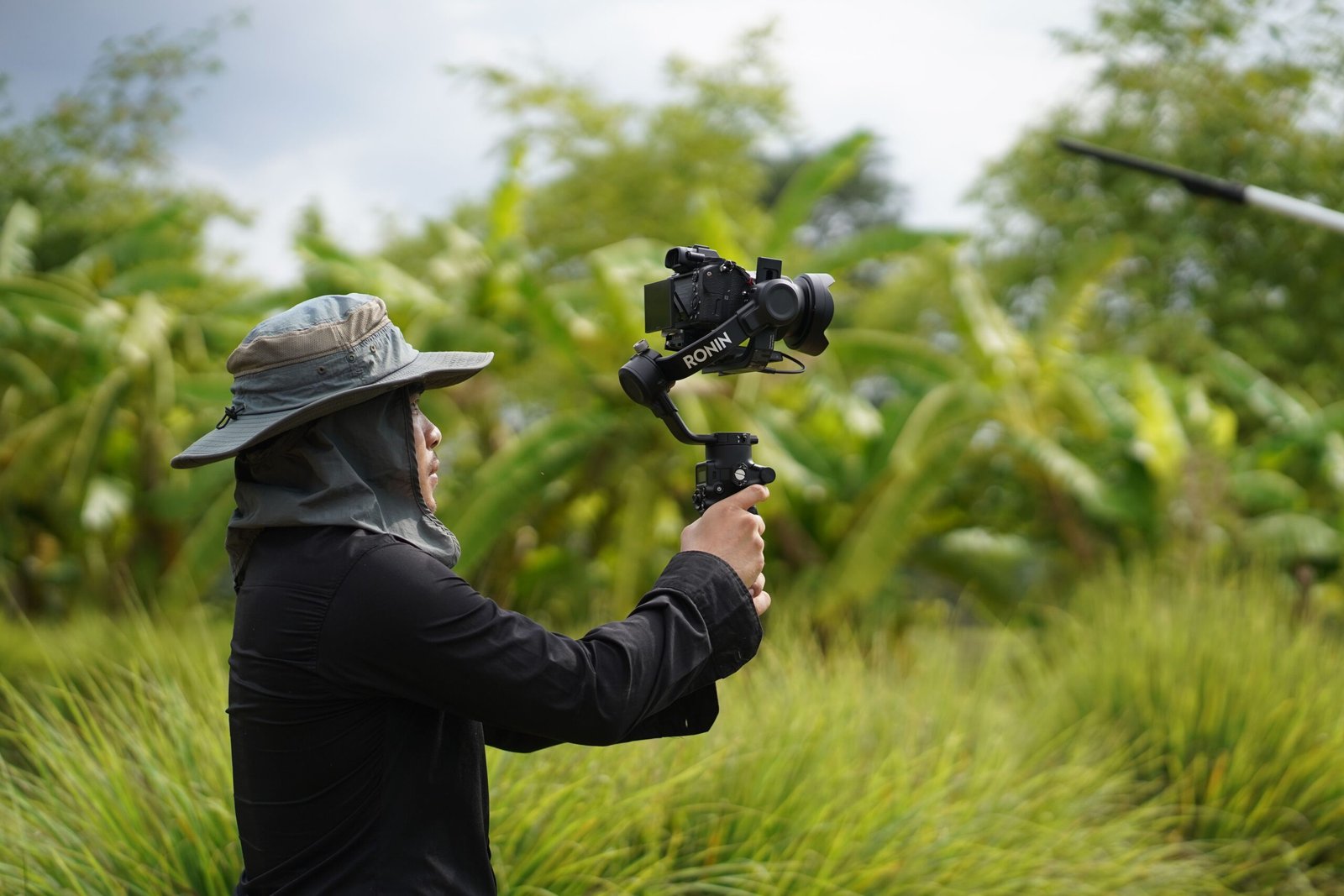 Cinematographer with stabilizer filming in lush countryside, capturing nature's essence