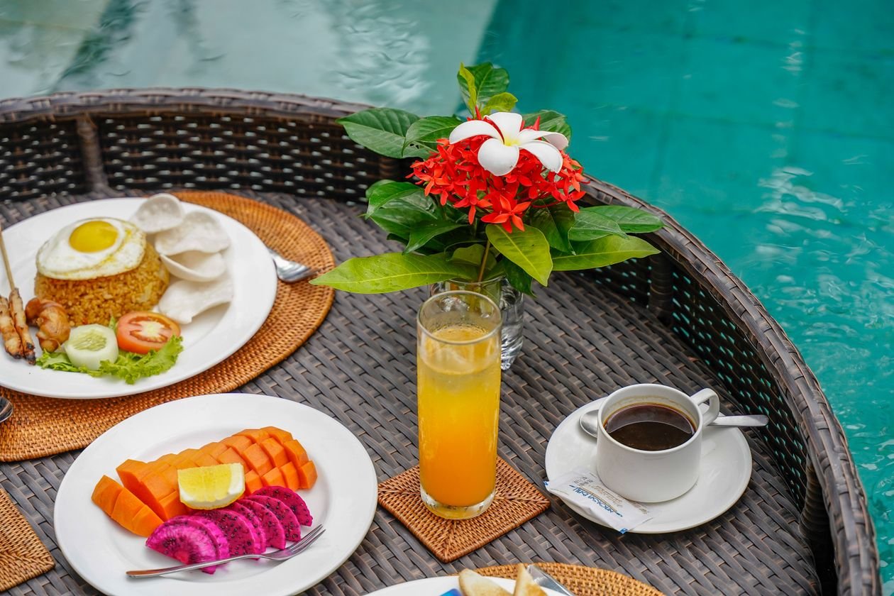 A vibrant poolside breakfast in Bali with tropical fruits, rice dish, and fresh coffee