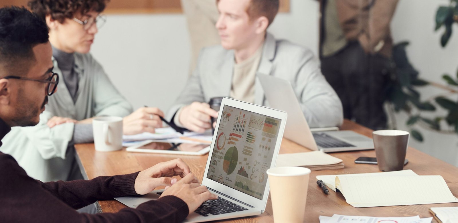 Team discussing marketing budget and campaign performance in a meeting, with a laptop showing charts