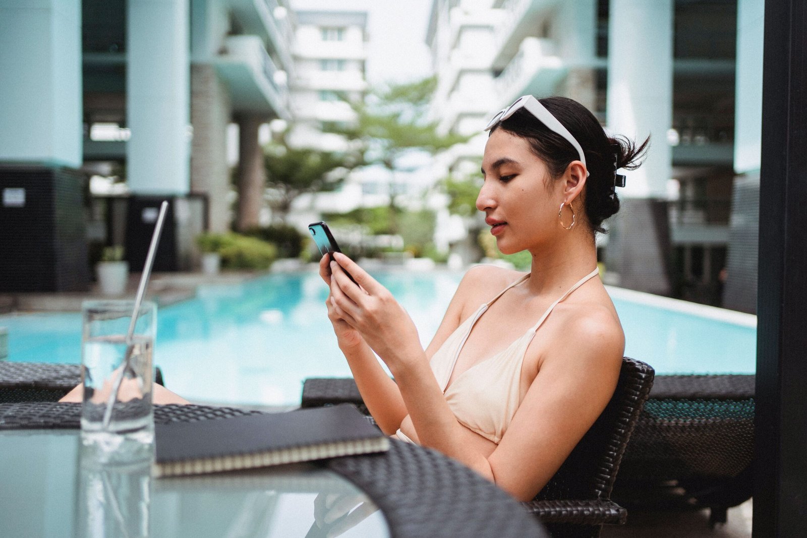 Woman relaxing by a hotel pool while scrolling on her smartphone, where retargeting ads reach travelers