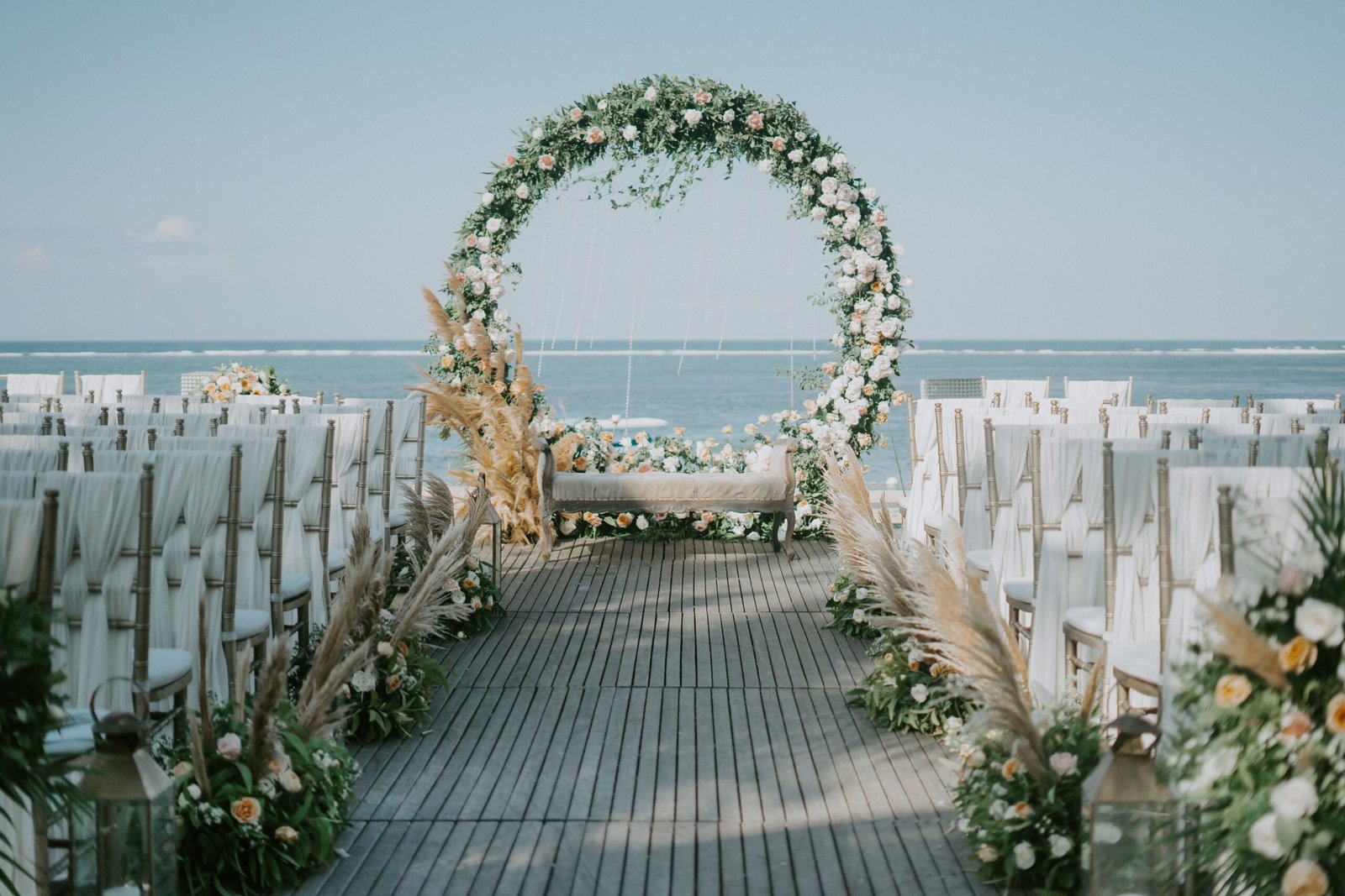 Beautiful beachside wedding setup with elegant floral arch and ocean backdrop